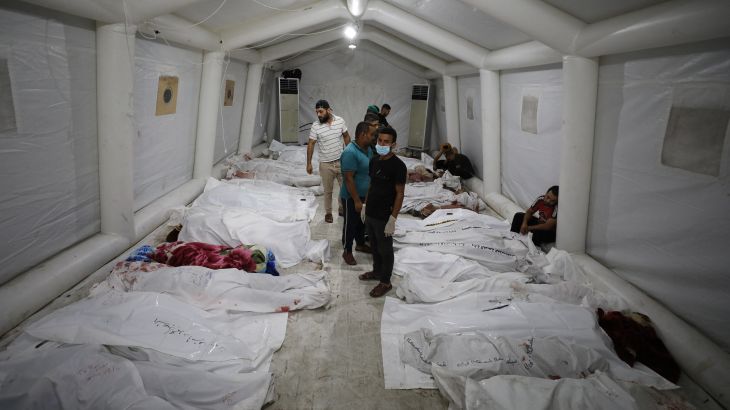 Graphic content / People stand over bodies of Palestinians killed after a blast ripped through the Ahli Arab hospital