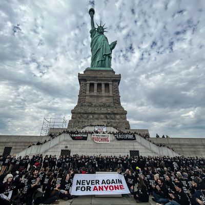 A group of people sitting on stairs with a statue of liberty

Description automatically generated