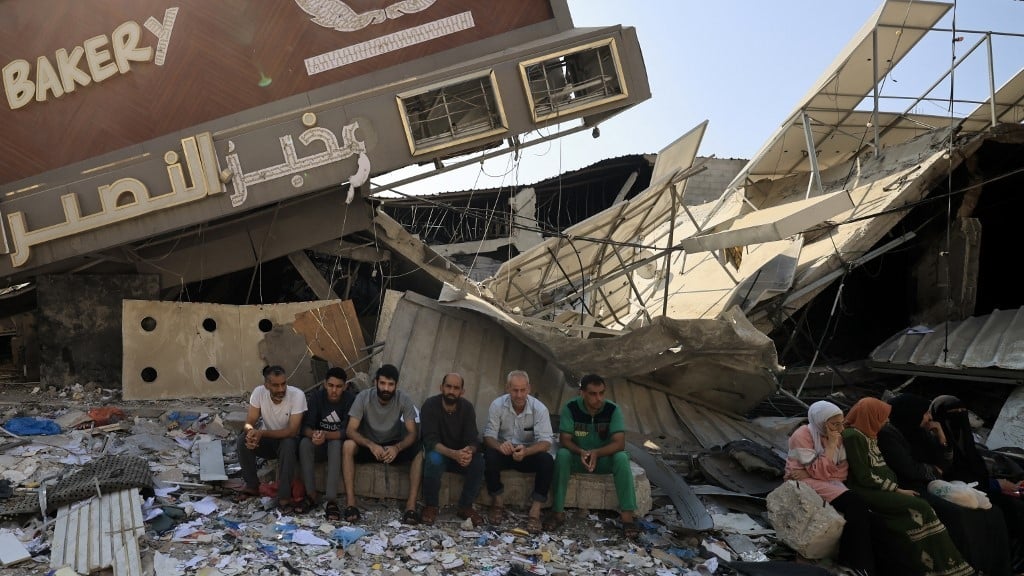 A group of men sitting in front of a collapsed building

Description automatically generated