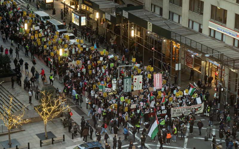 Hundreds of demonstrators march in the roadway. Pro-Palestine demonstrators march in protest of the US and US operated companies for their support of Israel during the Israel/Palestine conflict. The demonstration continued past Wall Stret after word of the US vetoing the UN Security Council's draft resolution that calls for an immediate ceasefire reached organizers. Image: Derek French/SOPA Images/Sipa USA