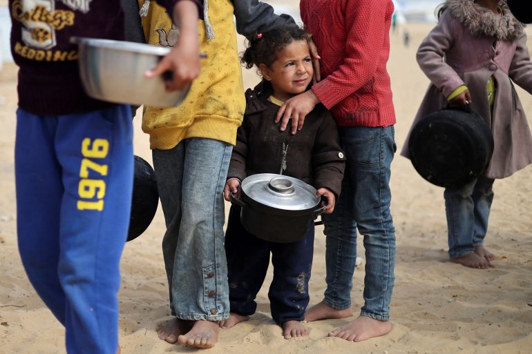 Displaced Palestinian children wait to receive food at a tent camp in Rafah in the southern Gaza Strip, February 27, 2024.