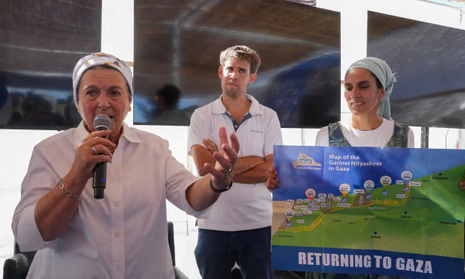 A woman speaks into a microphone with a younger man and woman to her left, the woman holding a sign with a map with the words 'Returning to Gaza' written beneath in capitals