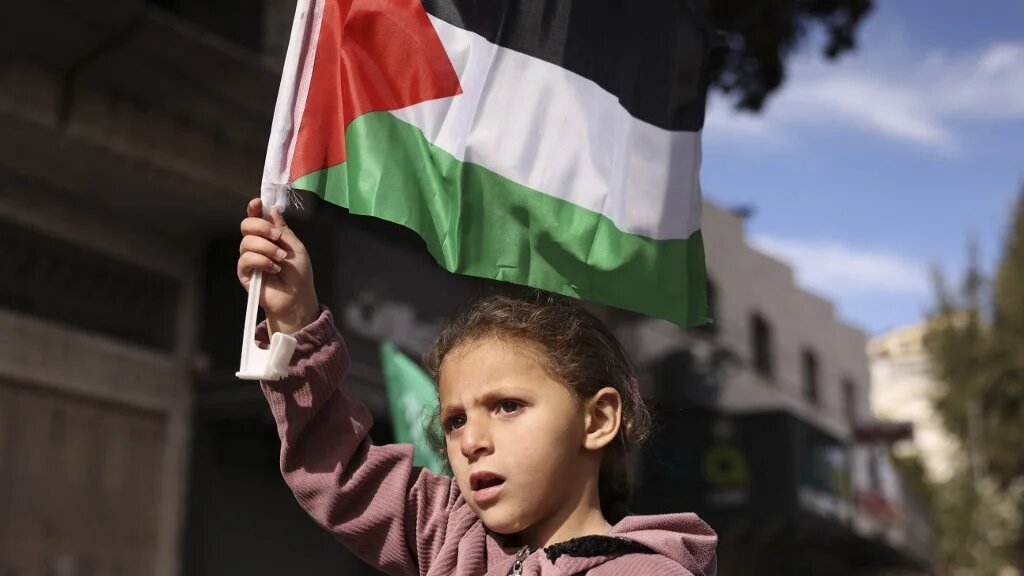 A girl lifts a Palestinian flag in Hebron, in the occupied West Bank, during a demonstration against the Gaza war on 8 December 2023 (Hazem Bader/AFP)