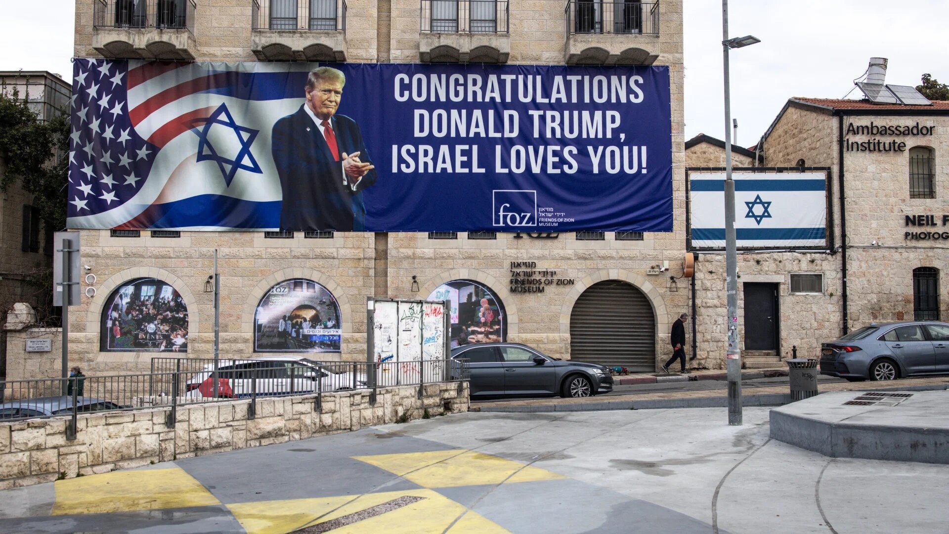 A man walks under a banner addressed to the US president reading “Congratulations Donald Trump, Israel loves you”, in Jerusalem, on 24 January 2025 (John Wessels/AFP)