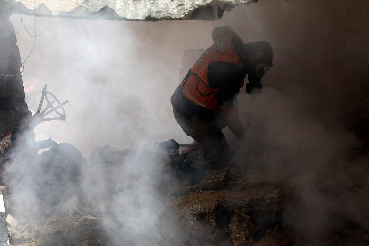 Palestinian rescue workers search for bodies and survivors under the rubble of a destroyed residential building following Israeli bombardment in Gaza City, Gaza Strip, May 16, 2021. (Mohammed Zaanoun/Activestills)