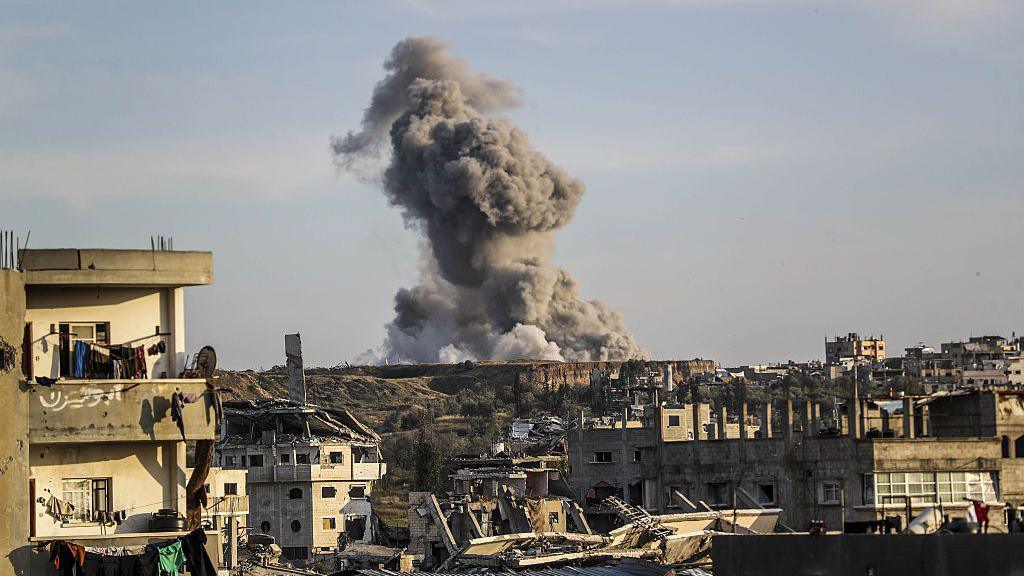 Smoke rises behind damaged buildings in Gaza City after an Israeli strike in the area.