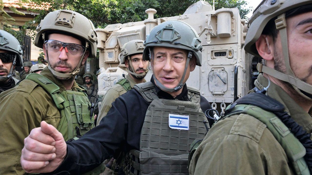 Israeli Prime Minister Benjamin Netanyahu, center, wears a protective vest and helmet as he receives a security briefing.