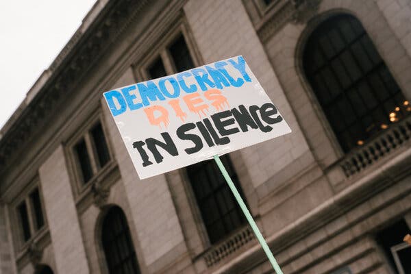 A photo of a sign that reads, “Democracy dies in silence.”