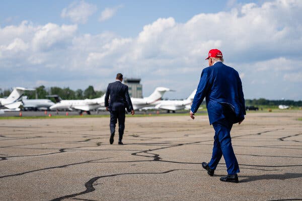 Donald Trump walks on a tarmac with his back to the camera.