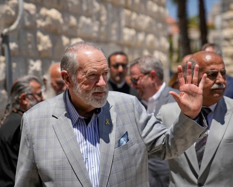 a man in a grey jacket waves