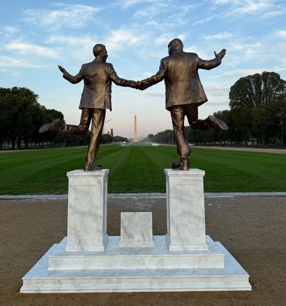 Trump and Epstein appear to be happily frolicking toward the Washington Monument in a new statue put there by The Secret Handshake, a small anonymous group
