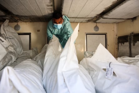 A hospital employee checks the remains of a Palestinians released by Israel under a Gaza ceasefire and hostage exchange deal, inside a refrigerated truck in front of the Nasser hospital in Khan Yunis in Gaza.