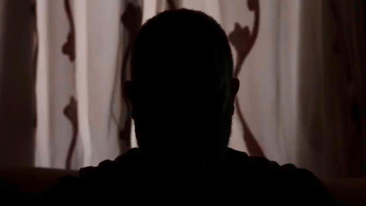 A picture taken from the BBC's anonymous interview with Ahmed, which is not his real name. He is seen in silhouette only, in front of a closed set of curtains in a dark room. 