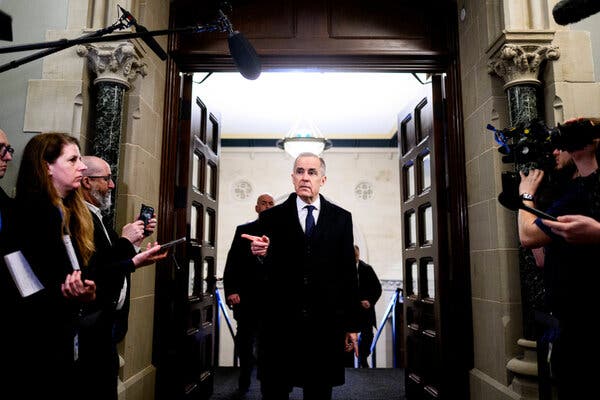 Mr. Carney, in a dark coat and tie, pointing a finger forward as he speaks with reporters.