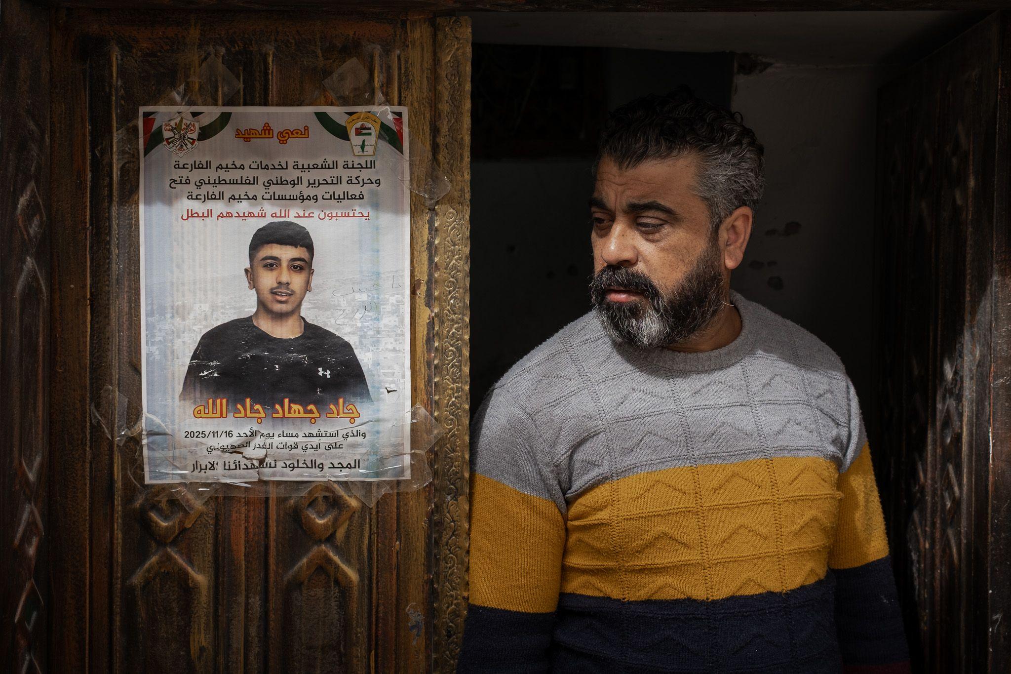 Jad's father stands next to a memorial poster of his son, taped to the family's carved wooden front door in al-Far'a refugee camp, in the occupied West Bank