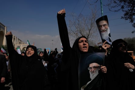 Women hold pictures of Ali Khamenei, chant and raise their fists while marching in the street