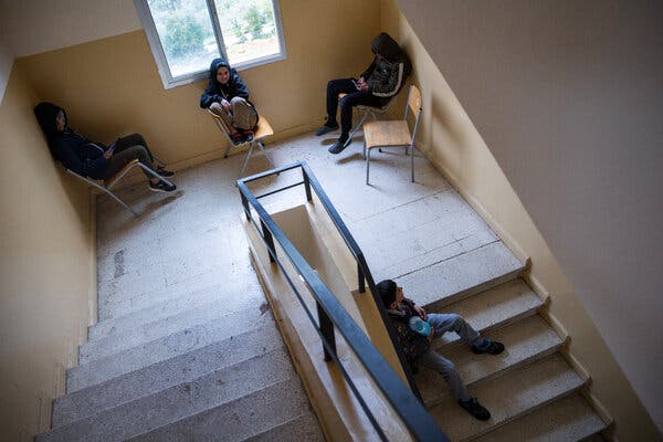 Children sitting on chairs in a stairway at a school.