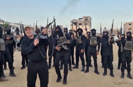 Hussam al-Astal fires a weapon in the air as he is surrounded by masked gunmen
