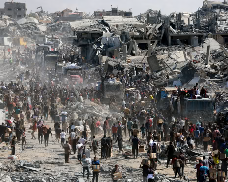 Large crowds gather amid destroyed buildings in Gaza, collecting boxes from aid trucks