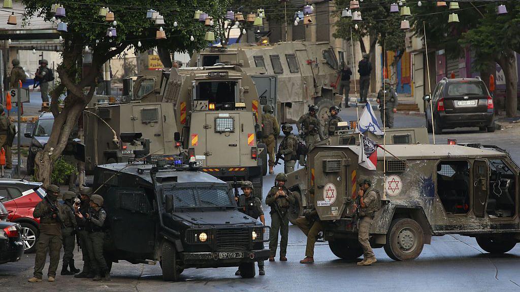 IDF vehicles and personnel block a road in the West Bank