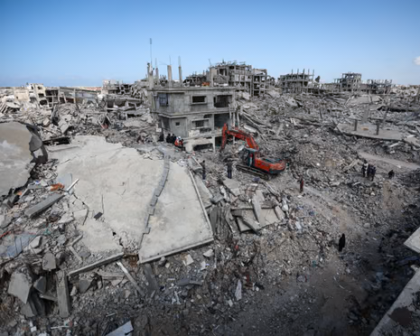 In Gaza City, an excavator and workers search rubble of buildings destroyed in Israeli attacks