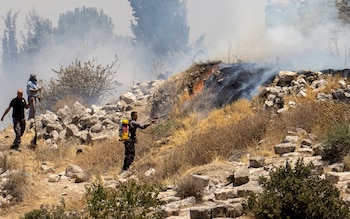 People try to put out the flames of a fire in Taybeh