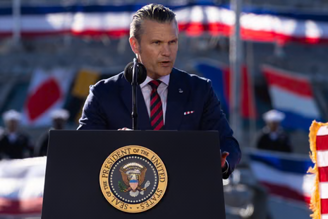 Pete Hegseth speaks at a presidential lectern outdoors during an event